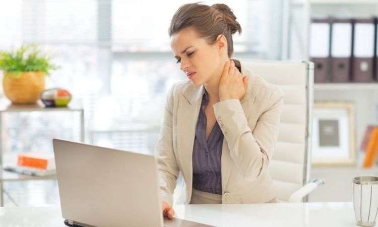 Una persona trabajando en una PC o celular con un collarín